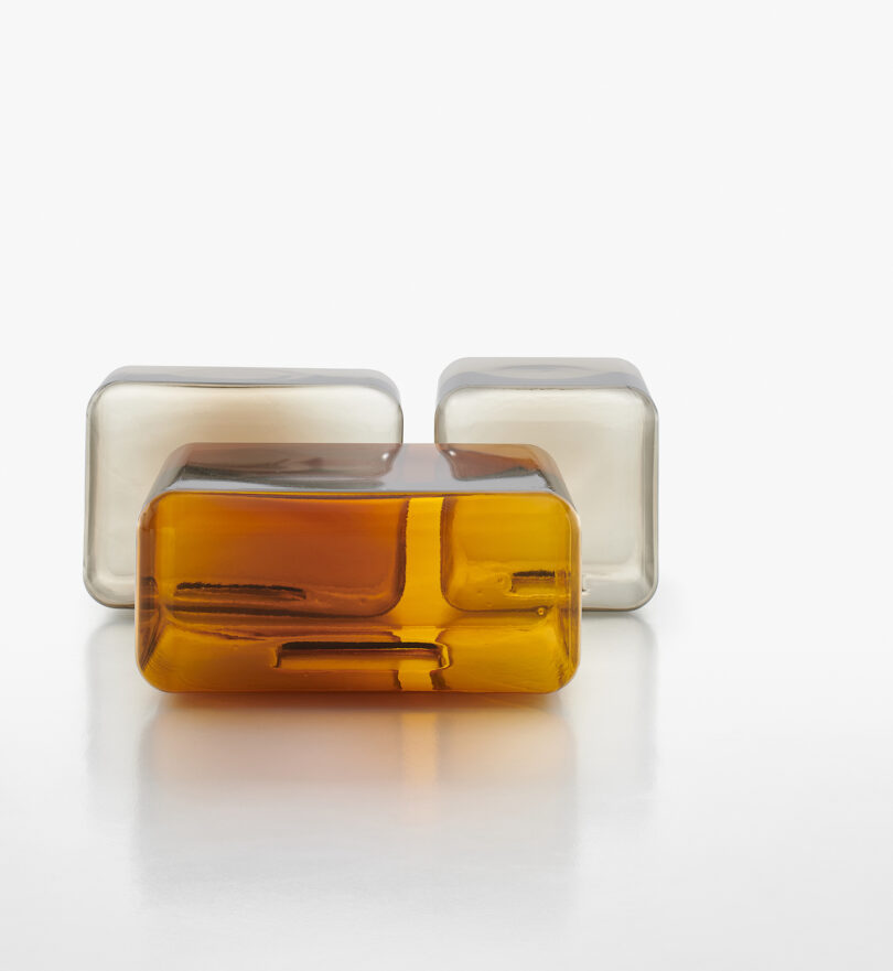 three translucent and amber glass tables arranged neatly on a white surface.