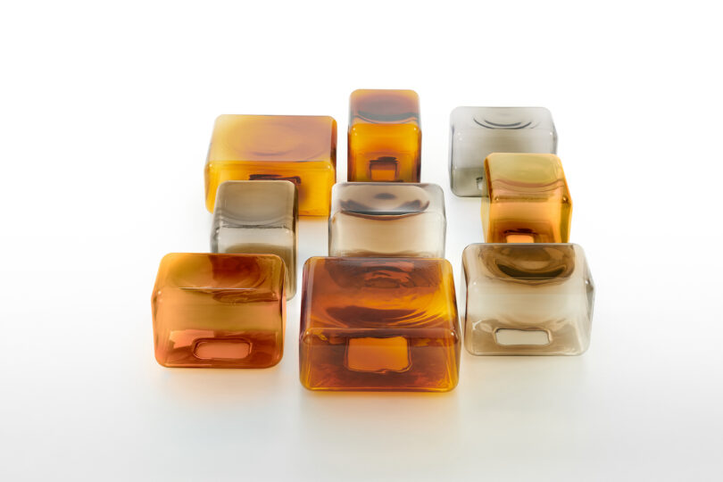 nine translucent and amber glass tables arranged neatly on a white surface.