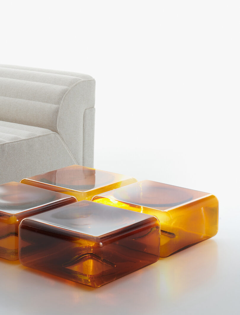four amber glass tables arranged neatly on a white surface next to a white sofa