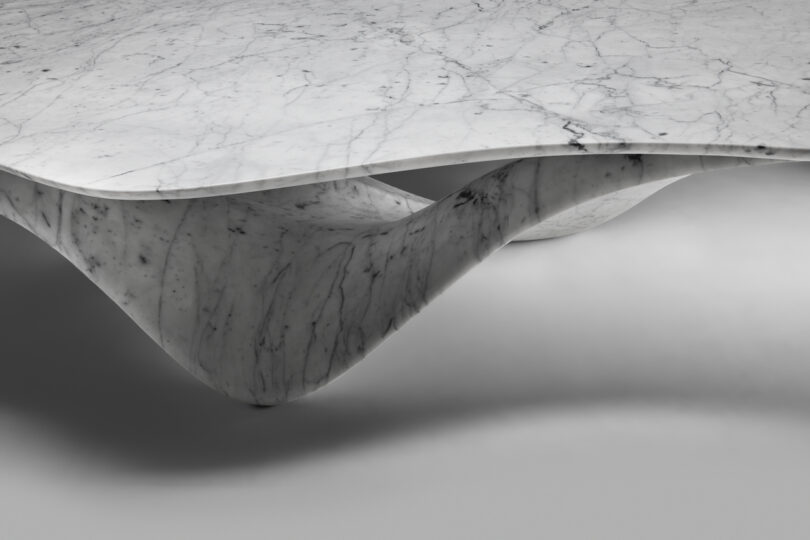 up close details of a sleek, modern marble sculpture with a symmetrical, eye-shaped hollow center, displayed against a shadowy background