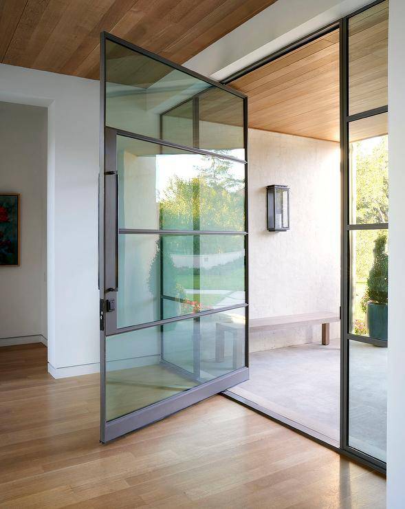 Stunning home boasts a glass and bronze swivel front door flanked by sidelights and fixed beneath a brown plank entry ceiling.