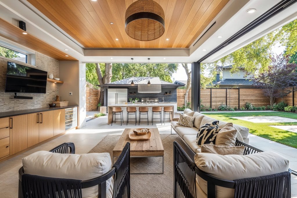 Elegant back patio design featuring cozy seating and lush greenery by Decorilla