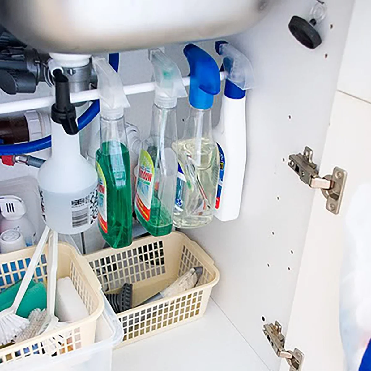 spray bottles hanging from tension rod under kitchen cabinet.