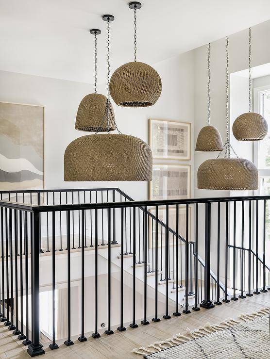 Cottage style iron staircase is illuminated by staggered basket pendants.