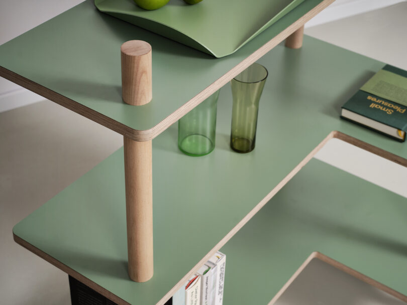 three tired green shelf with various objects placed on it