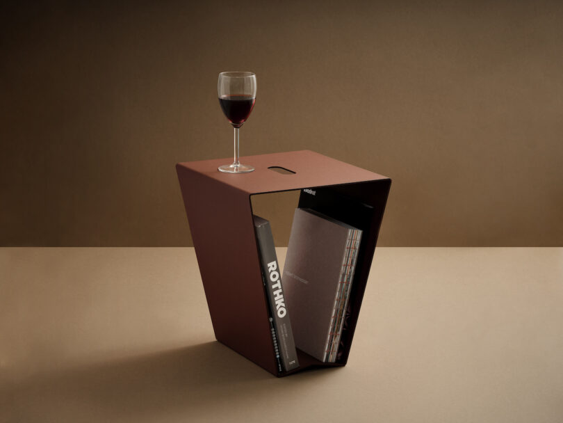 brown aluminum side table with a glass of wine placed on top and books stored inside