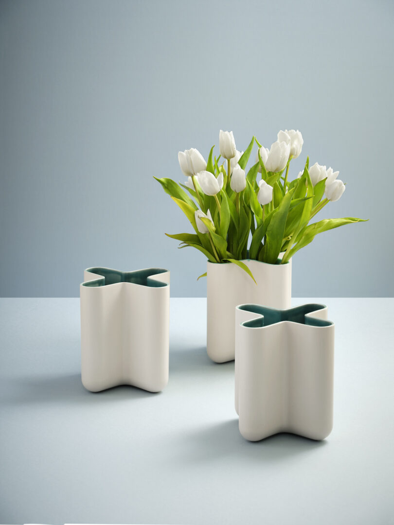 three x-shaped vases, one with white tulips placed inside