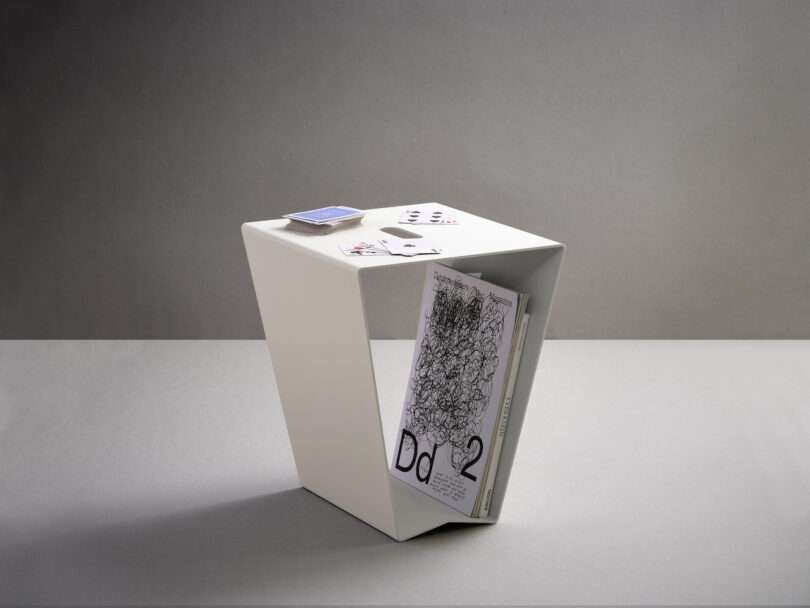 white aluminum side table with playing cards placed on top and magazines stored inside