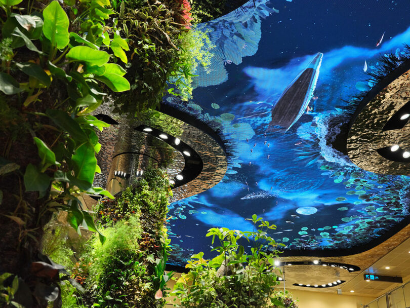 LED ceiling display depicting a whale swimming underwater among plants and foliage indoors.