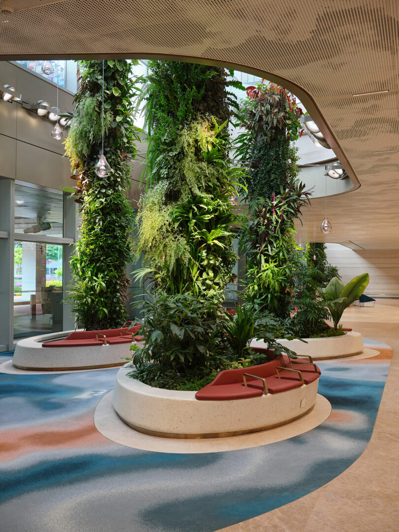 An indoor space with vertical gardens, red seating, and modern, curved architectural design elements.