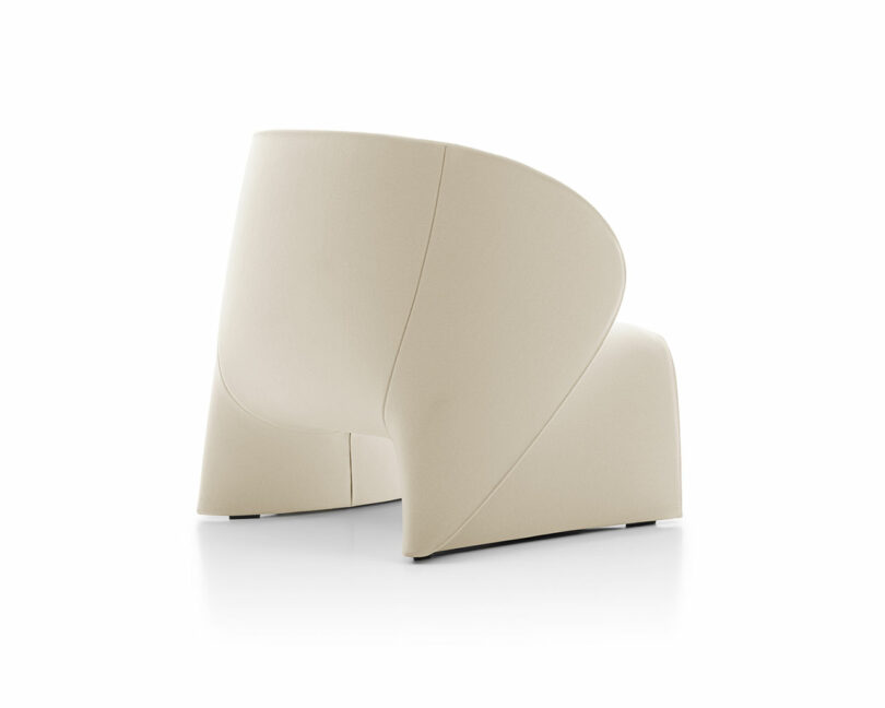 A modern beige upholstered chair with a unique, curved design viewed from the back.