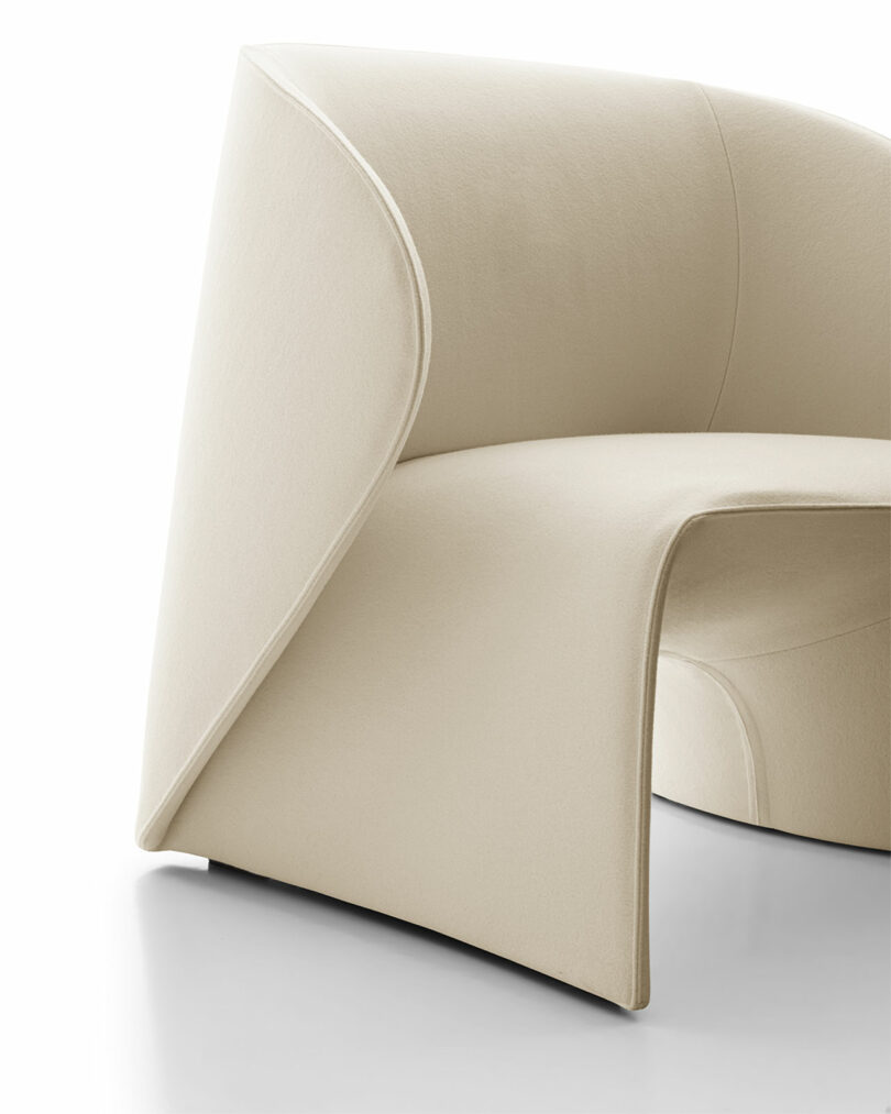 A modern cream-colored chair with a unique, curvilinear design featuring smooth lines and a minimalist aesthetic.