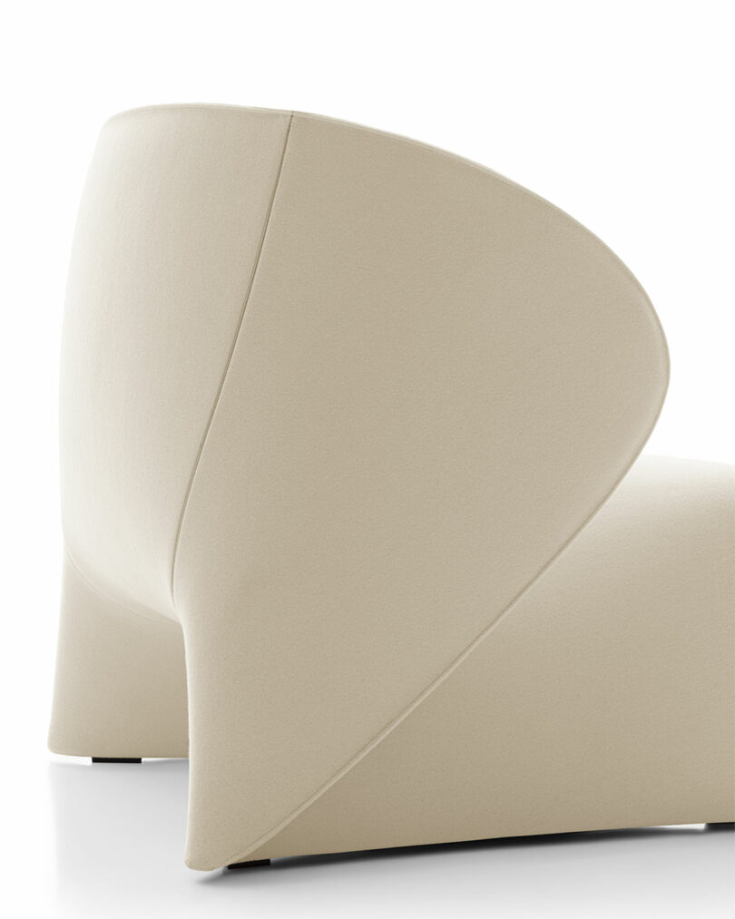 A modern beige chair with a curved backrest and minimalist design, set against a white background.