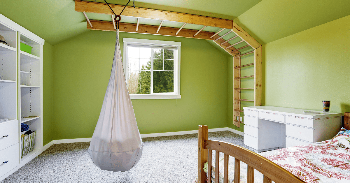 A fabric hanging chair in a green bedroom.