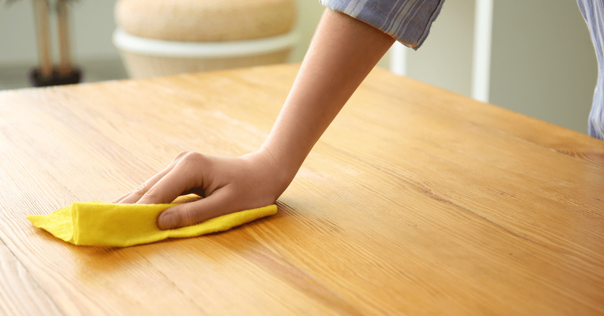 Wiping wooden furniture to clean it.