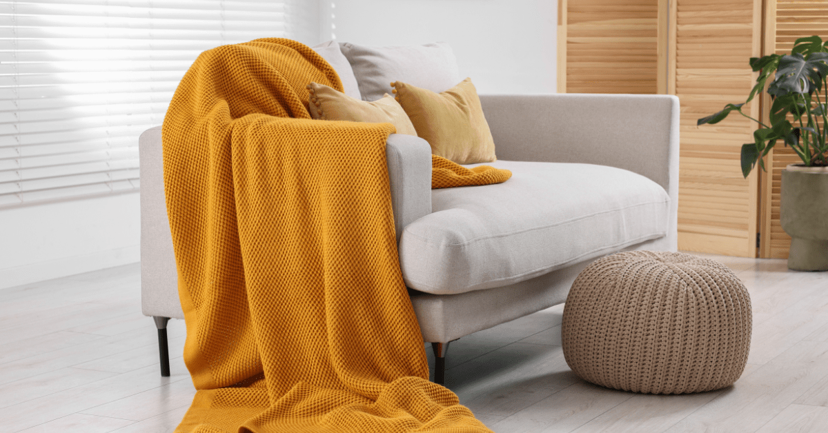 White couch with orange throw blanket