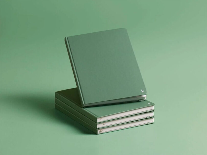 A stack of four green notebooks, with one leaning against the others, is set against a matching green background.