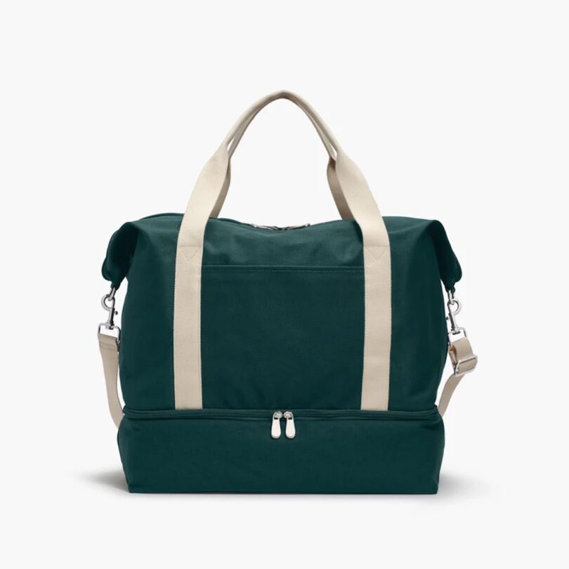 A green weekender bag from Lo & Sons with white handles and shoulder strap