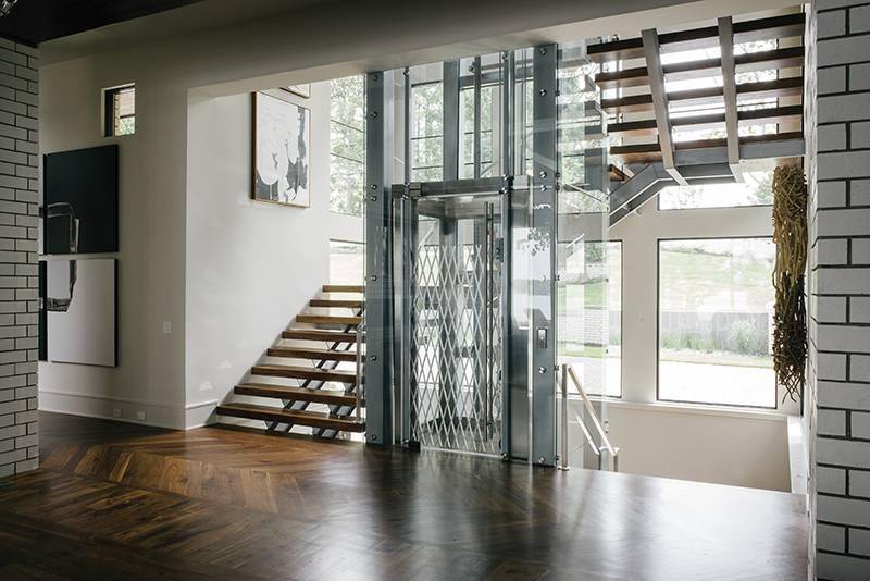 Glass elevator with stairs surrounding it.