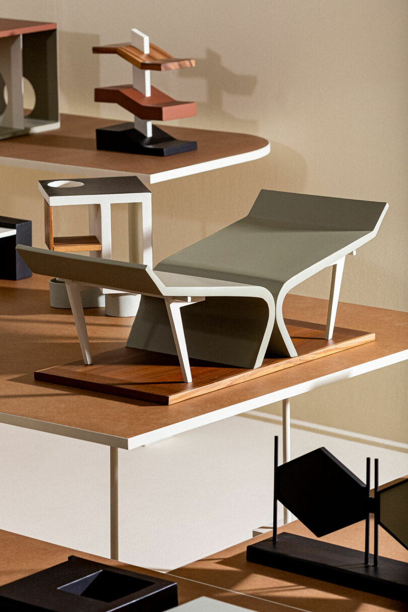 Multiple abstract geometric sculptures are displayed on tiered shelves. The sculptures vary in shape and color, including angular and curved designs in neutral and muted tones