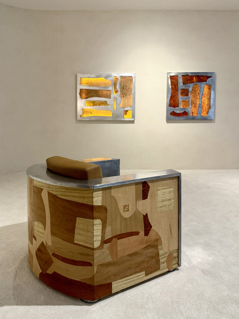 A modern gallery space with two abstract paintings on the wall and a uniquely designed wooden reception desk in the foreground.