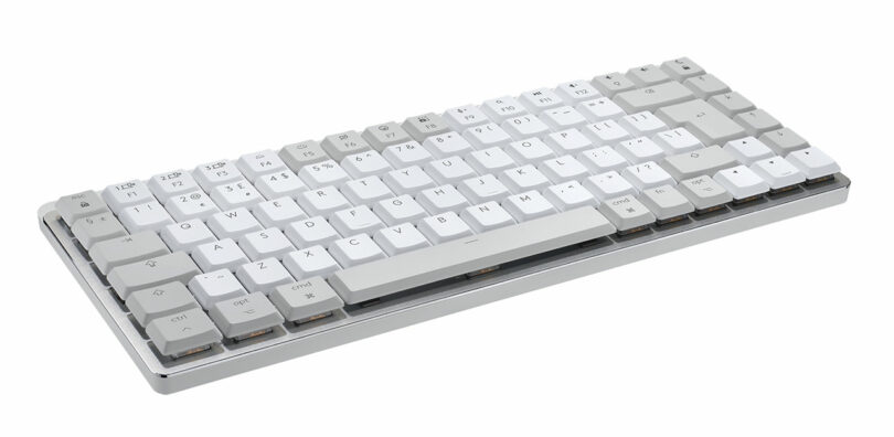 A compact mechanical keyboard designed by Giulio Barresi, featuring light gray and white keys on a pristine white background.