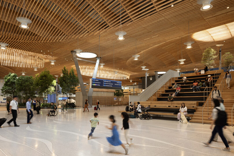 The ZGF-designed airport terminal boasts wooden ceilings, lush trees, and ample seating. As travelers stroll and relax on the steps, a digital sign suspended from above keeps everyone informed.