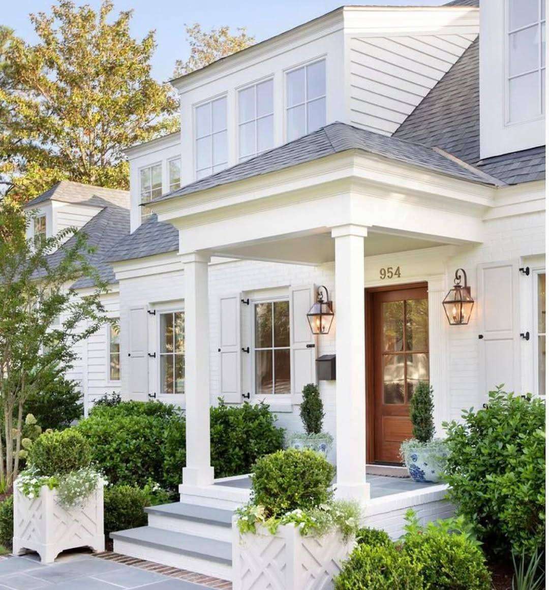 An angled shot of the front of a home with white trim and siding.