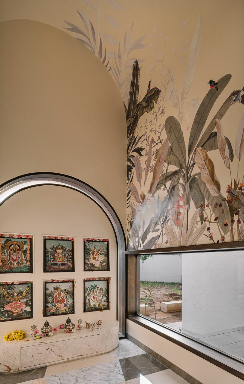 A room with a curved arch wall featuring botanical wall art and several framed artworks. There are small decorations and flowers placed on a marble table.