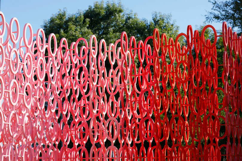 A red sculpture made of interlocking circular rings, reminiscent of Emmanuelle Moureaux's 