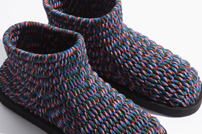 Colorful woven slippers with a textured, braided design featuring red, blue, and green hues, set against a plain white background.