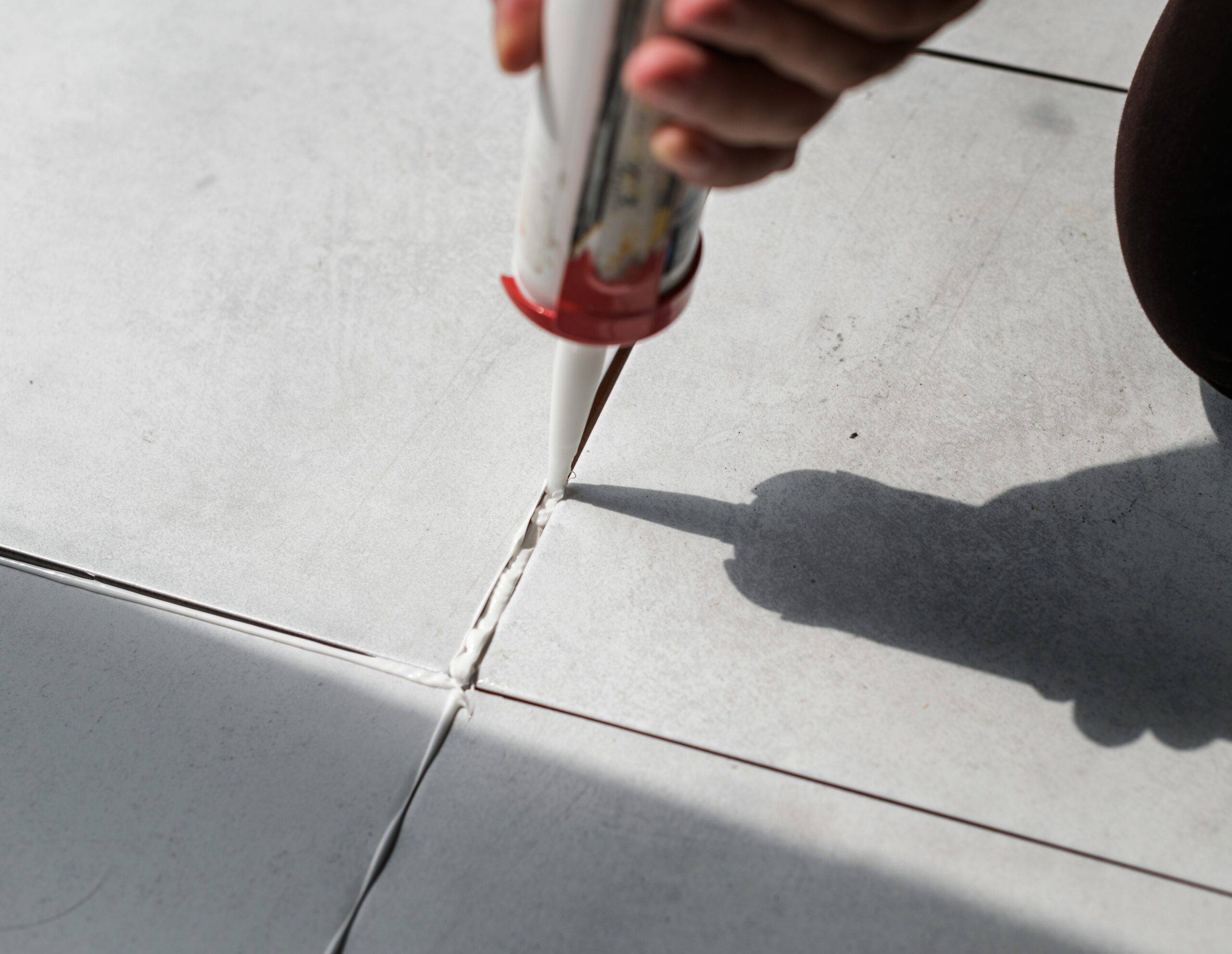 A close photo of someone filling gaps between tiles.