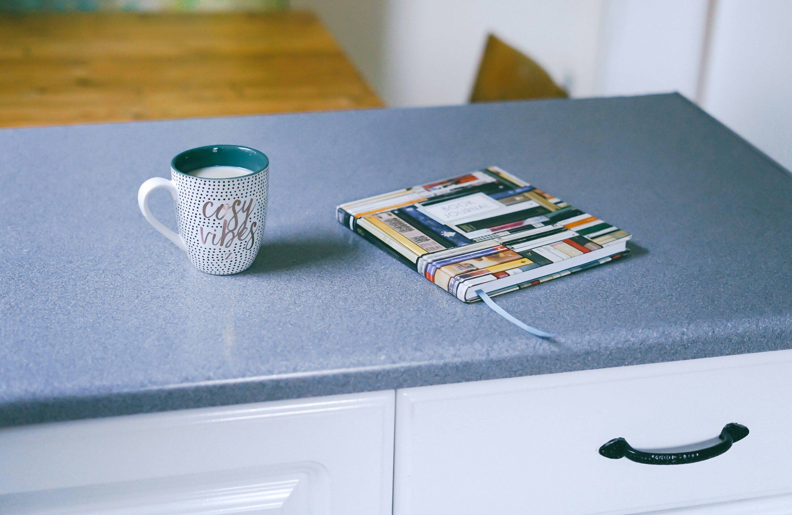 A kitchen counter with a mug and journal on it.