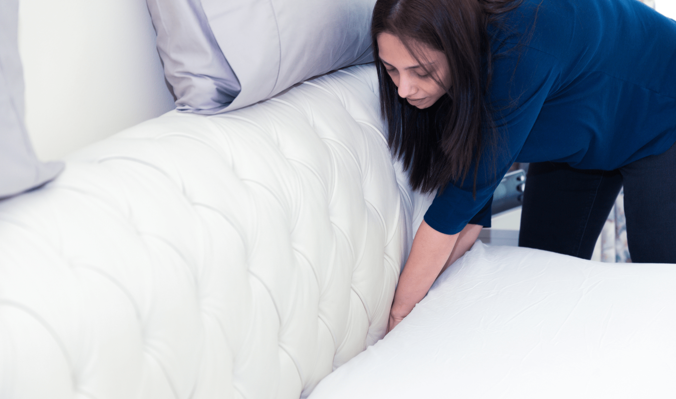 A woman tucking her flat sheet into her mattress.