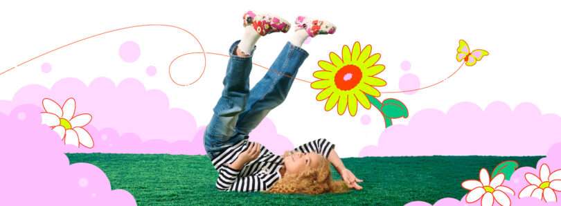 A young child with curly hair lies on green grass with legs playfully raised, surrounded by illustrated flowers, pink clouds, and a butterfly on a white background