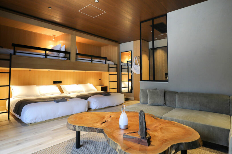 Modern TRUNK(HOTEL) CAT STREET room with two double beds, two top bunk beds, a large green sectional sofa, and a wooden coffee table with minimalist decor