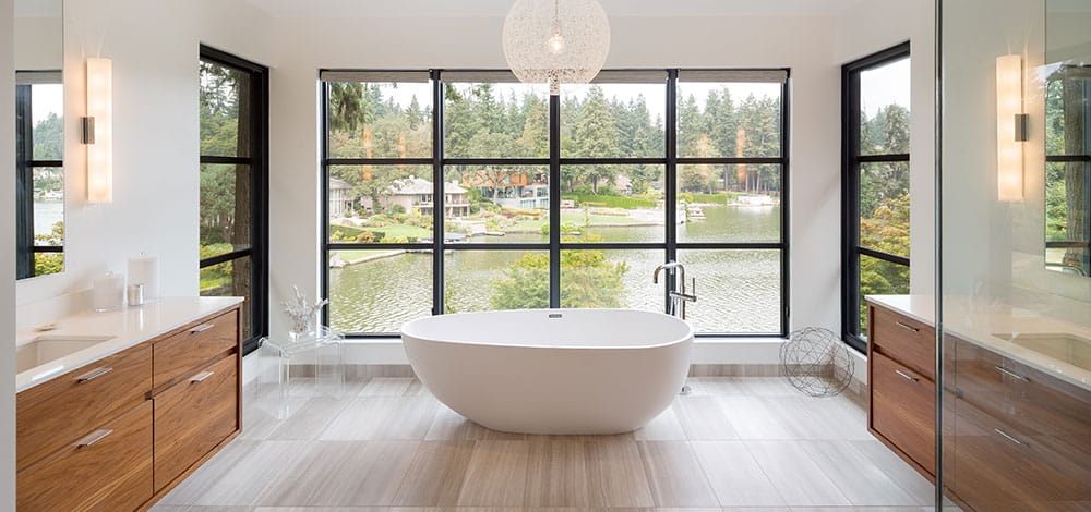 Modern primary bathroom design with a large window by DECORILLA designer, Autumn M. 