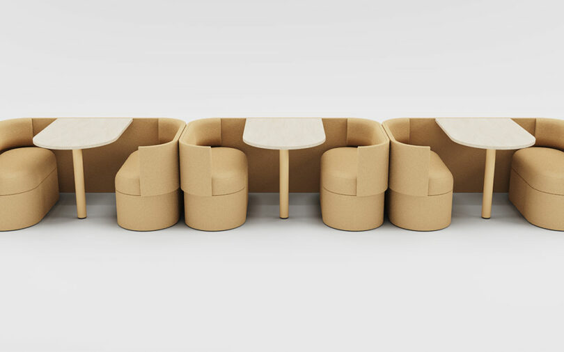 A row of modern beige booth seating with round tables and curved chairs arranged against a plain white background.