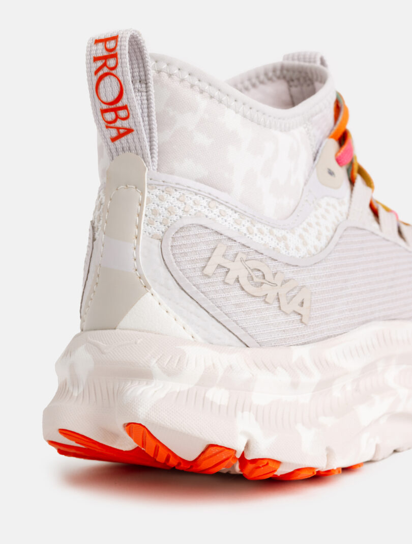 Close-up of the heel and side of a white Hoka running shoe with red-orange accents, textured sole, and