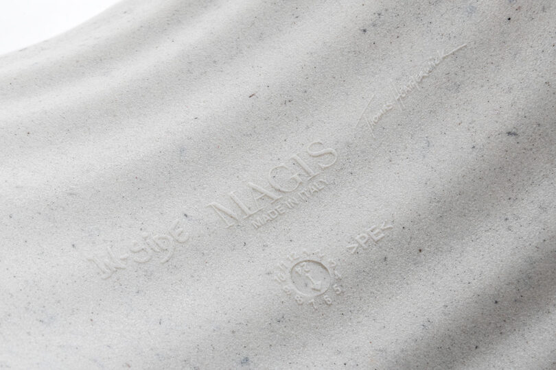 Close-up of embossed branding and text on a light gray textured surface, featuring 