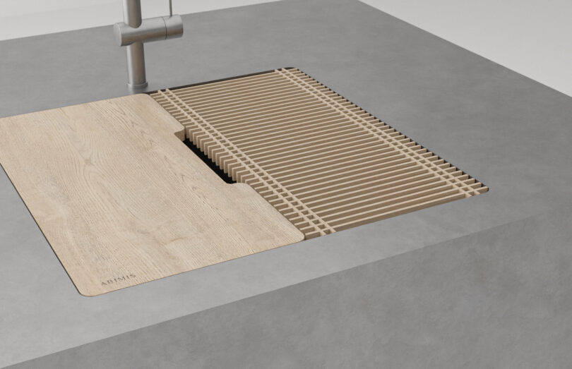 A modern kitchen sink with a wooden slatted dish rack and matching wooden cover set into a gray countertop