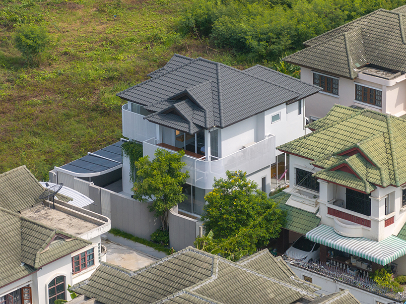 curved textile facades wrap reborn house in bangkok village emitting soft glow