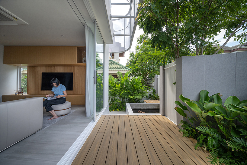 curved textile facades wrap reborn house in bangkok village emitting soft glow