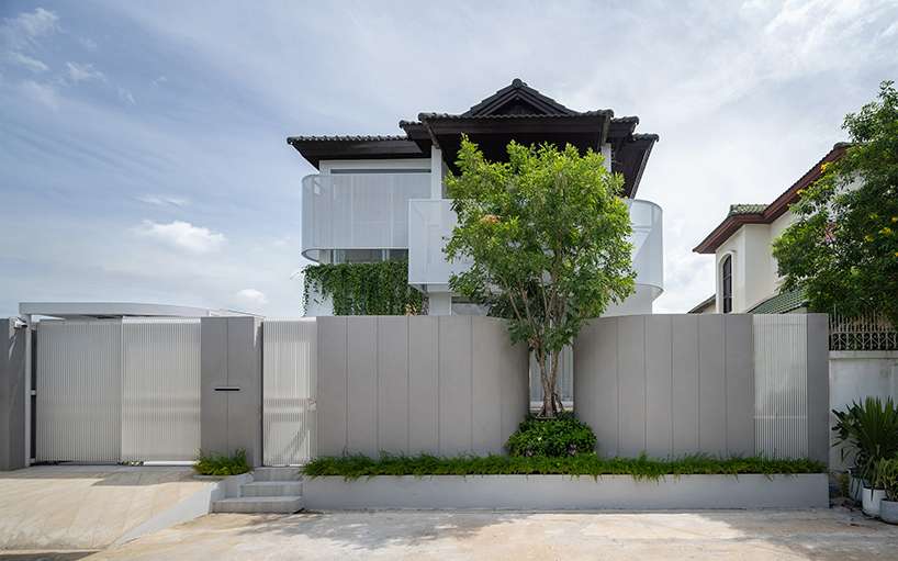 curved textile facades wrap reborn house in bangkok village emitting soft glow