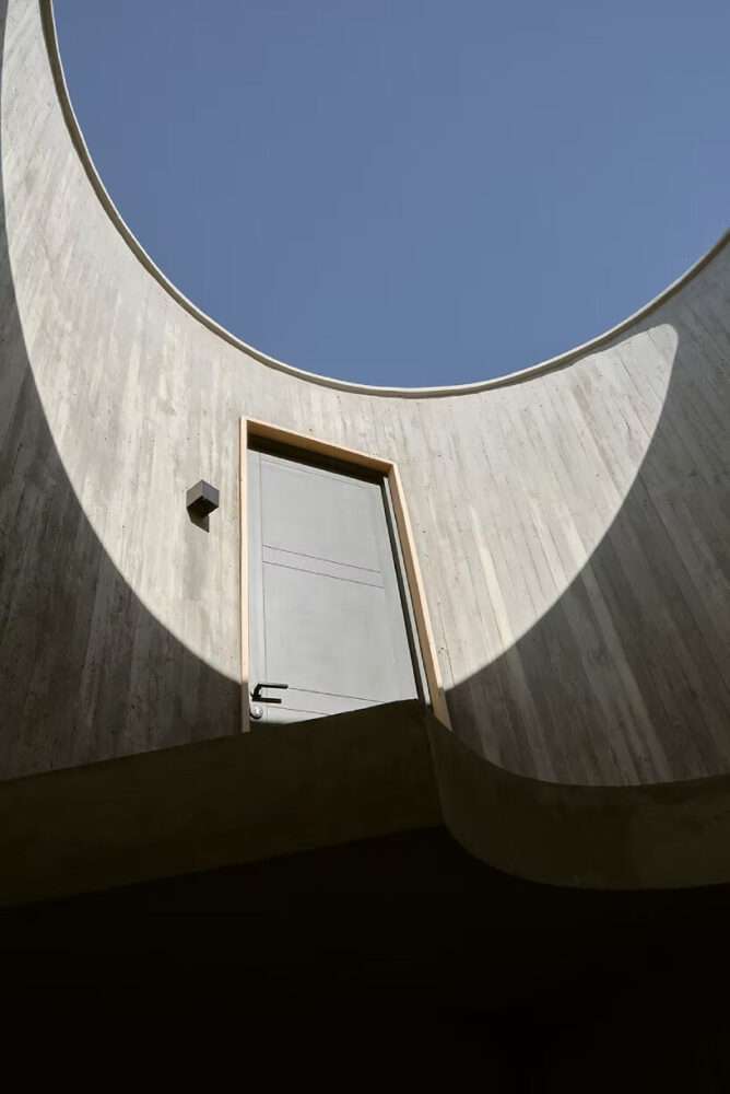 wooden beams sit atop concrete spiral staircase in lote studio’s elevated casa CG in chile
