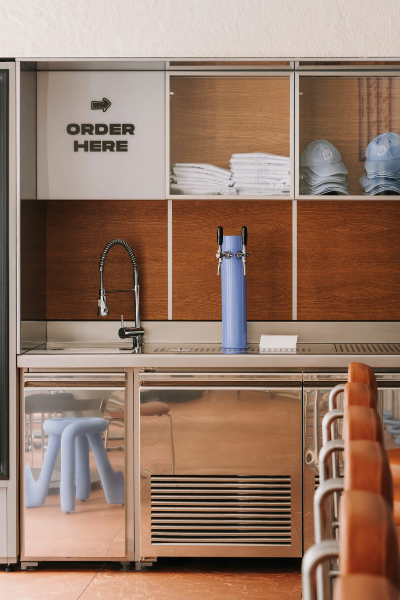 A modern counter with a blue Pluto beverage tap, sink, and an 