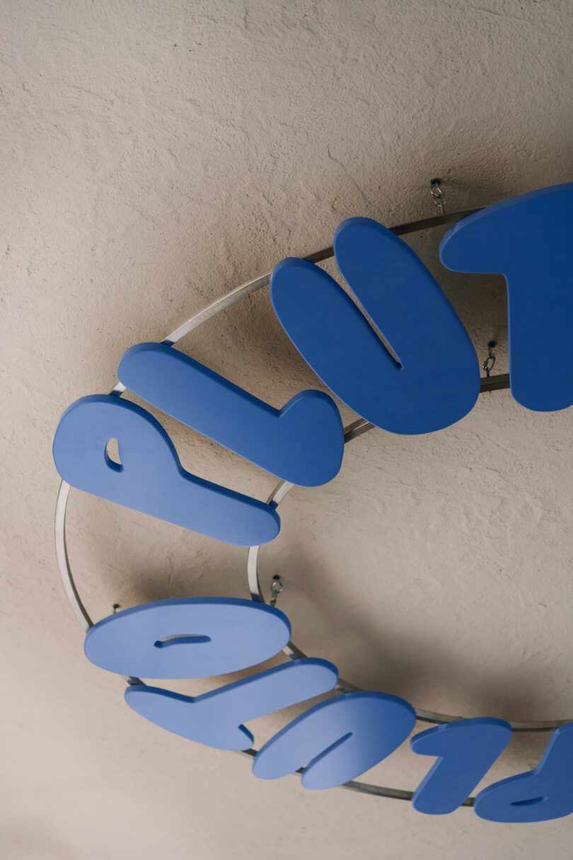 A partial view of a circular metal frame with large blue letters, possibly spelling 