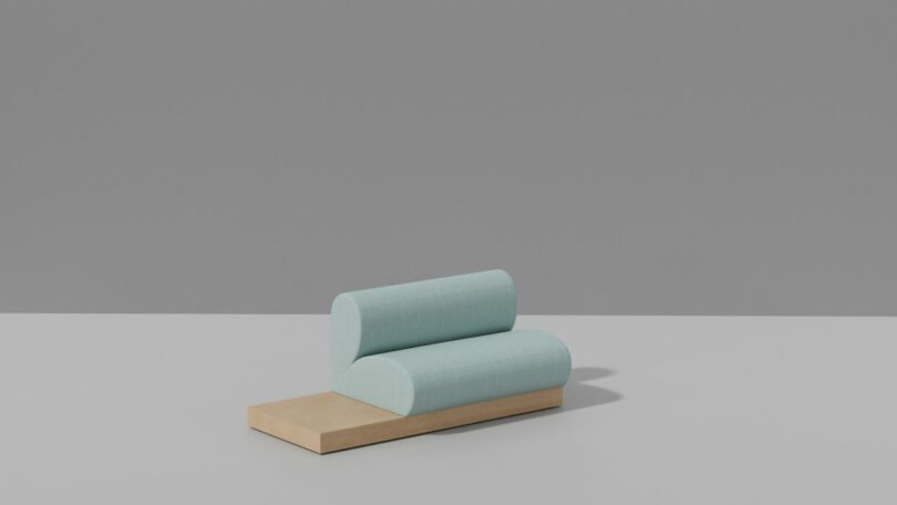 A minimalist sculpture featuring two light blue, candy-like cylindrical cushions stacked on a rectangular wooden base against a plain grey background.