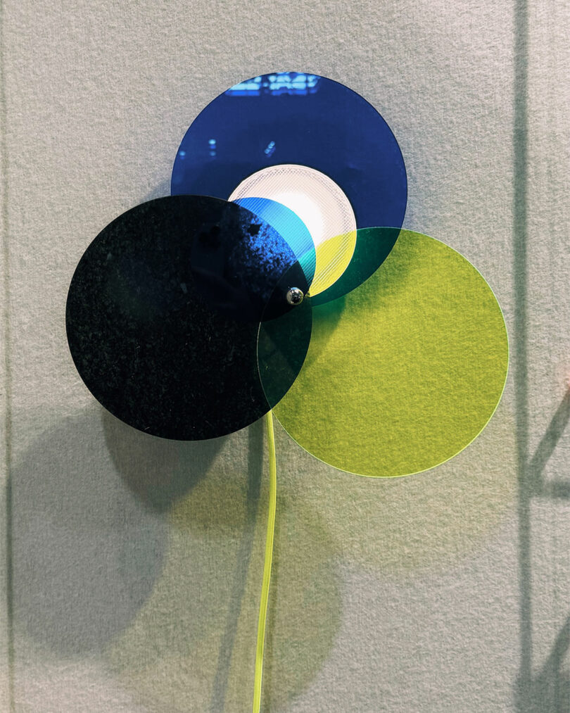 Three overlapping translucent circles—navy, blue, and yellow—are pinned together on a light textured wall at Maison & Objet, creating layered color effects.