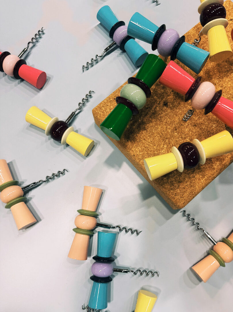 Colorful corkscrews with rounded, bead-like handles are scattered on a light surface, some resting on a cork board—a playful Maison & Objet-inspired touch for any modern kitchen.
